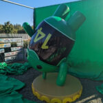 An Android robot wearing a jersey with the number 14 on it doing a handstand on a piece of pineapple upside-down cake. 